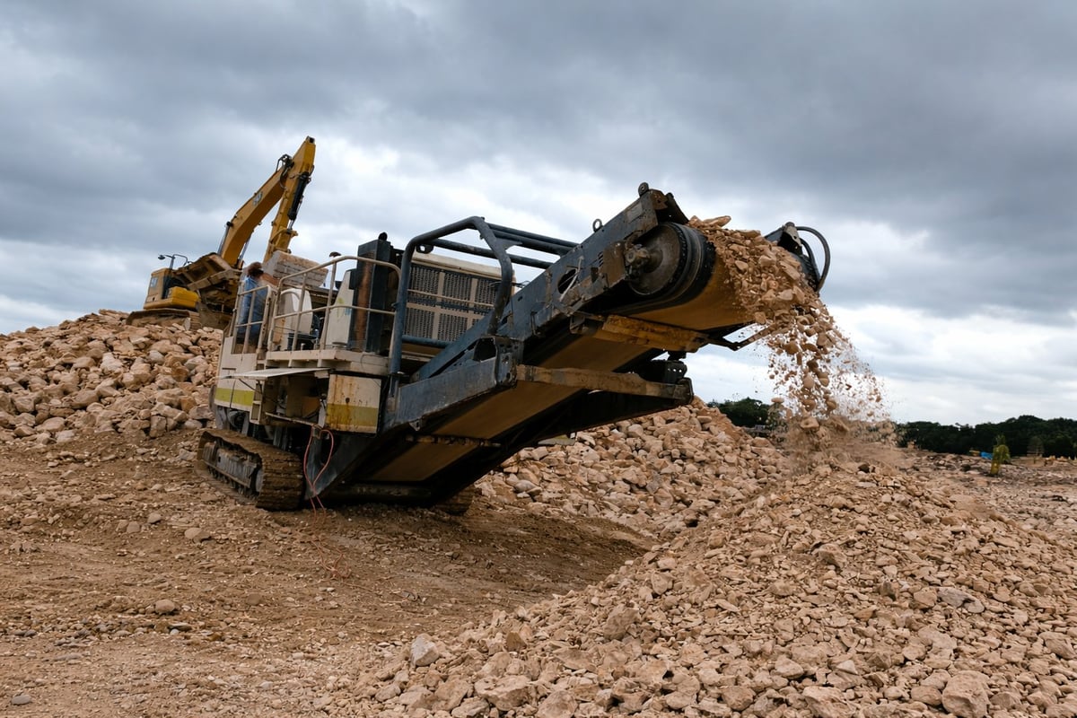 Mobile rock crusher equipment processing aggregate material at a construction or mining site